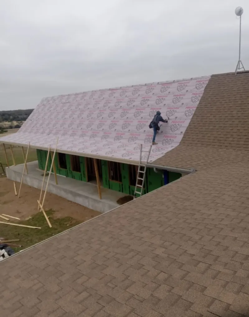 Worker preparing underlayment for a metal roof installation in Coventry